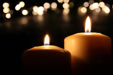 Bokeh parlak ışıklı siyah arka plan üzerinde yanan mumlar