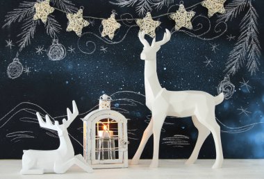 Kara tahta arka plan whith el üzerinde ahşap masa üzerinde beyaz Ren geyiği tebeşir illüstrasyonlar çizilmiş