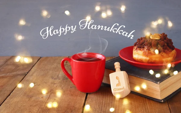 Imagem de feriado judaico Hanukkah com donuts, tampo giratório de madeira, xícara de chocolate quente e livro velho . — Fotografia de Stock