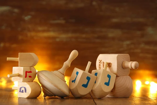 Image of jewish holiday Hanukkah with wooden dreidels colection (spinning top) and glowing gold lights