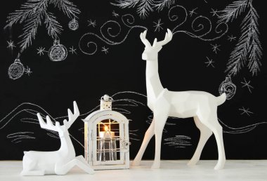 Ahşap masa üzerinde el ile kara tahta arka plan üzerinde beyaz Ren geyiği tebeşir illüstrasyonlar çizilmiş.