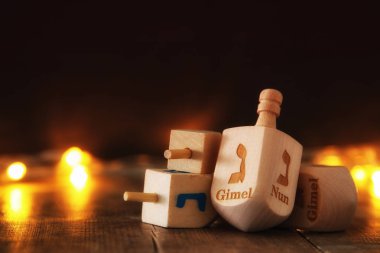 Image of jewish holiday Hanukkah with wooden dreidels colection (spinning top) and glowing gold lights clipart