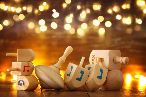 Imagen de la fiesta judía Hanukkah con la colección dreidels de madera (peonza) y luces doradas brillantes —  Fotos de Stock