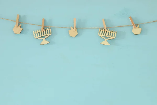 jewish holiday Hanukkah background with decorative wooden menorah (traditional candelabra) and spinning tops hanging on a rope