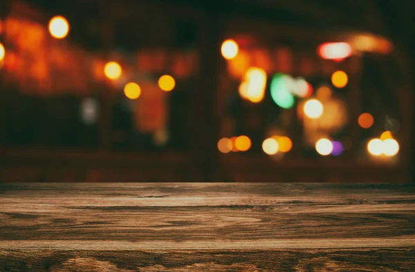 Image of wooden table in front of abstract blurred restaurant lights background — Stock Photo, Image