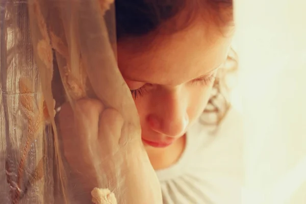 Porträtt av omtänksamt lilla flicka nära fönstret. Vintage filtrerade bilden. — Stockfoto