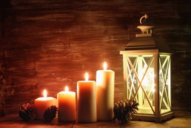 Ahşap masa üzerinde yanan mumlar ve çam kozalakları ile vintage fener.