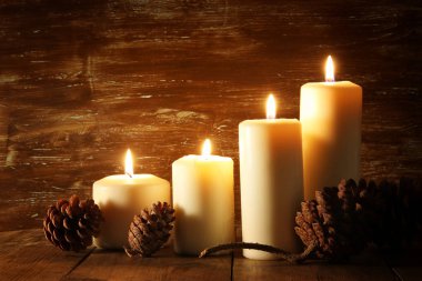 yanan mumlar ve çam kozalakları ahşap tablo.