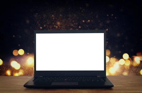 Offener Laptop mit weißem Bildschirm auf Holztisch vor abstraktem Glitzerhintergrund — Stockfoto