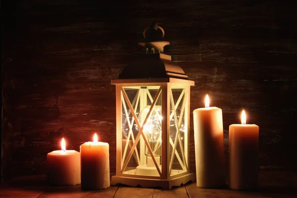 Lanterna vintage com velas em chamas e cones de pinho na mesa de madeira . — Fotografia de Stock