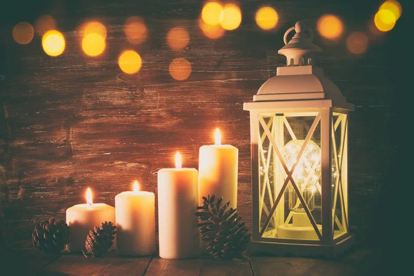 Linterna Vintage con velas encendidas y conos de pino sobre mesa de madera . — Foto de Stock
