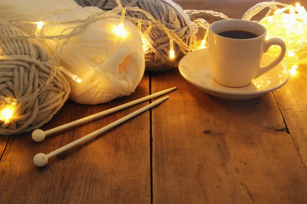 Boules de laine chaudes et confortables et tasse de café chaude sur une table en bois . — Photo
