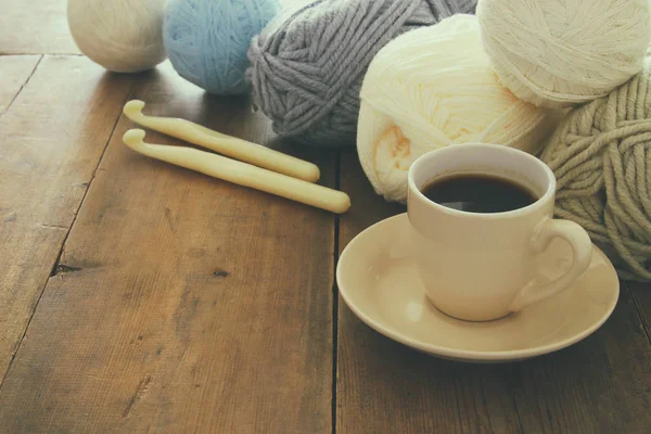 Cálidas y acogedoras bolas de lana y taza de café caliente en la mesa de madera . —  Fotos de Stock