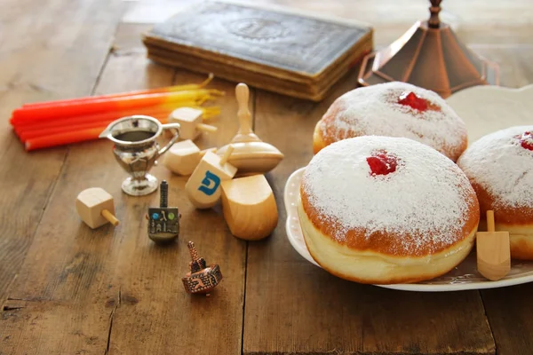 Bilden av judiska högtiden Hanukkah bakgrund med traditionella spinnig top, munkar och menorah (traditionella kandelabrar). — Stockfoto