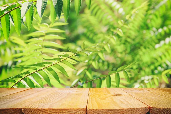 Meja kayu di depan latar belakang bunga hijau tropis. untuk tampilan produk dan presentasi. — Stok Foto