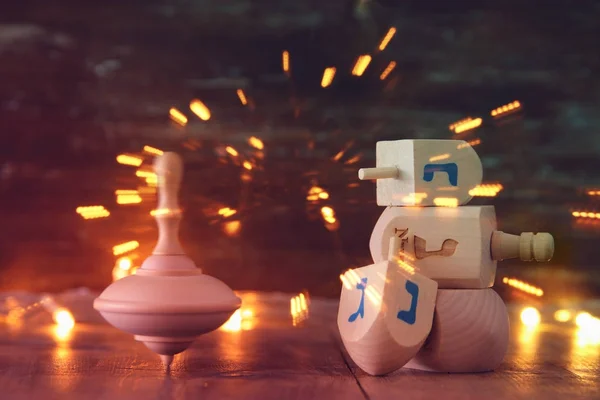 Joodse vakantie Hanukkah met houten dreidels collectie (spinnen boven) en gouden garland licht op tafel — Stockfoto