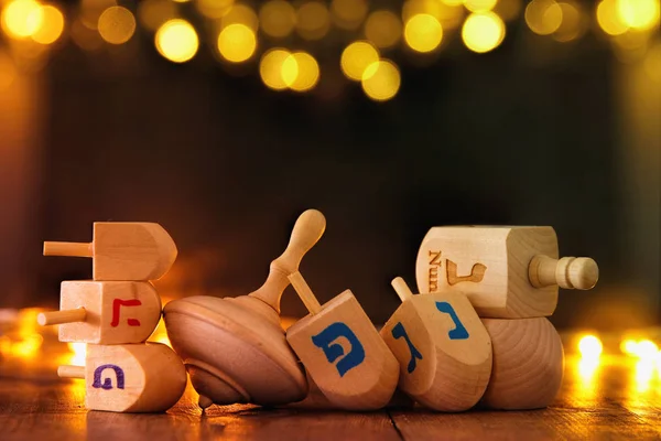 Vacaciones judías Hanukkah con la colección dreidels de madera (peonza) y luces de guirnalda de oro en la mesa —  Fotos de Stock