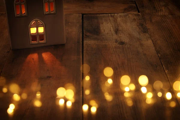 Imagem chave baixa da lanterna da casa com vela ardente e luz quente nas janelas sobre o fundo de madeira velho — Fotografia de Stock