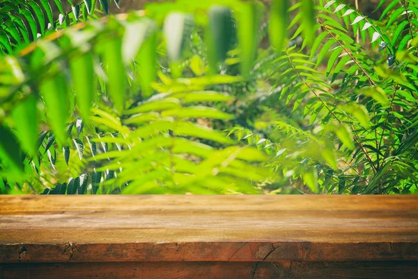 Table en bois devant un fond floral vert tropical. pour l'affichage et la présentation des produits. — Photo