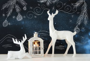 Ahşap masa üzerinde el ile kara tahta arka plan üzerinde beyaz Ren geyiği tebeşir illüstrasyonlar çizilmiş.