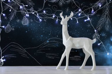 Kara tahta arka plan whith el üzerinde ahşap masa üzerinde beyaz Ren geyiği tebeşir illüstrasyonlar çizilmiş.