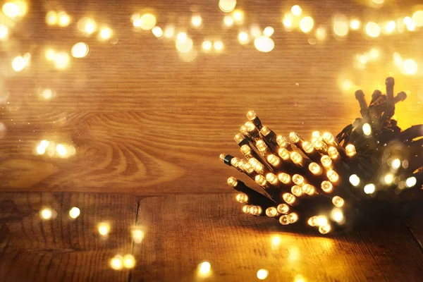 木製の素朴な背景にクリスマス温かみのあるゴールドのガーランド ライト。フィルターされたイメージ — ストック写真