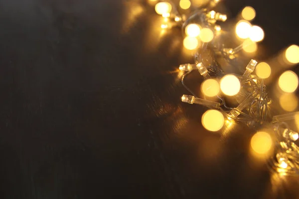 Navidad luces de guirnalda de oro caliente sobre el fondo de madera balck. Superposición de purpurina — Foto de Stock