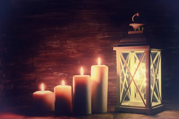 Linterna Vintage con velas encendidas y conos de pino sobre mesa de madera . — Foto de Stock