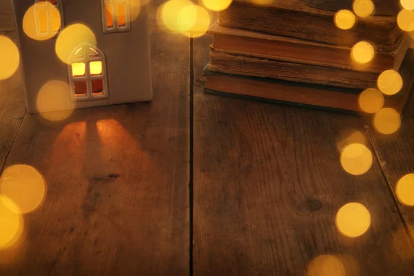 Immagine a chiave bassa della lanterna della casa con candela accesa e luce calda nelle finestre su vecchio sfondo di legno — Foto Stock