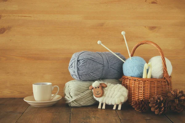 Warm and cozy yarn balls of wool and hot cup of coffee on wooden table. — Stock Photo, Image
