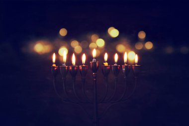 Low key image of jewish holiday Hanukkah background with menorah (traditional candelabra) and burning candles clipart