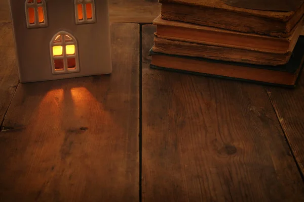 Imagem chave baixa da lanterna da casa com vela ardente e luz quente nas janelas sobre o fundo de madeira velho — Fotografia de Stock