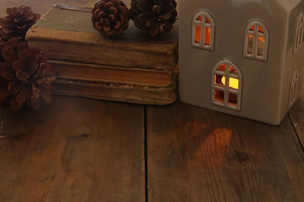 Imagen de baja llave de la linterna de la casa con vela encendida y luz cálida en las ventanas sobre fondo de madera viejo . —  Fotos de Stock