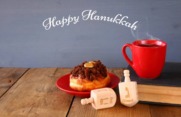 Imagem de feriado judaico Hanukkah com donuts, tampo giratório de madeira, xícara de chocolate quente e livro velho . — Fotografia de Stock