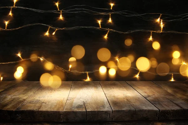 Mesa de madeira na frente do Natal luzes grinalda ouro quente no fundo rústico de madeira — Fotografia de Stock