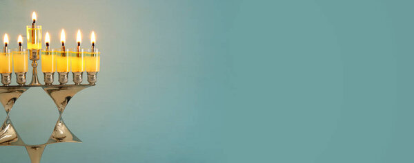 image of jewish holiday Hanukkah background with menorah (traditional candelabra) and burning candles.