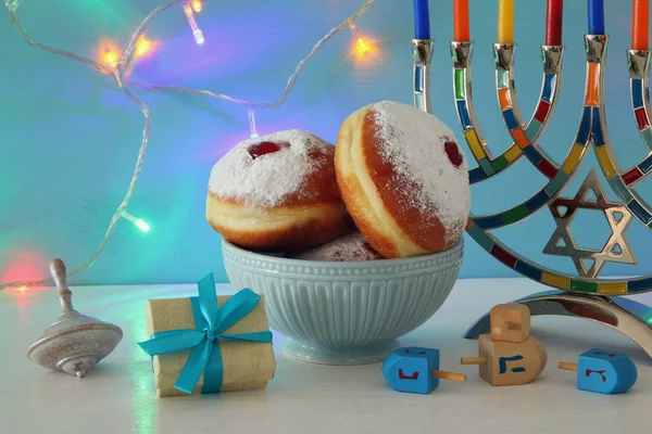 image of jewish holiday Hanukkah background with traditional spinnig top, menorah (traditional candelabra) and donut.