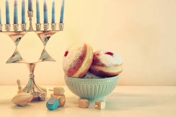 Image of jewish holiday Hanukkah background with traditional spinnig top, menorah (traditional candelabra) and donut. — Stock Photo, Image