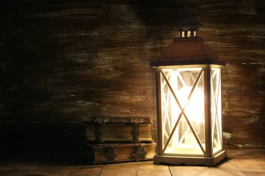 Ahşap masa üzerinde eski kitaplar yanındaki Vintage fener