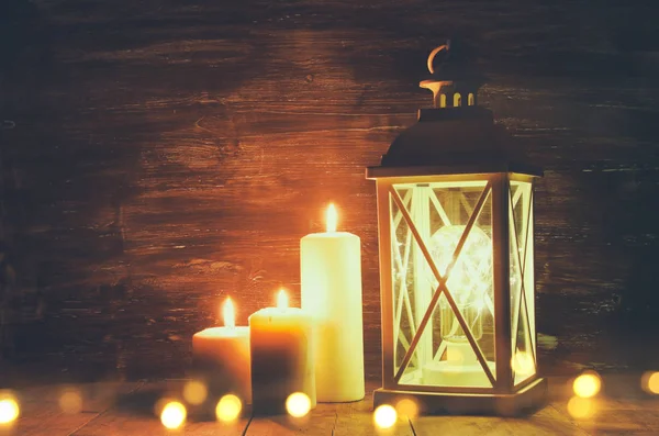 Lanterna vintage com velas em chamas na mesa de madeira . — Fotografia de Stock