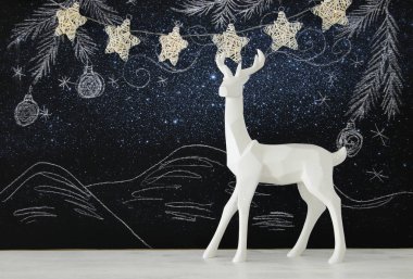 Kara tahta arka plan whith el üzerinde ahşap masa üzerinde beyaz Ren geyiği tebeşir illüstrasyonlar çizilmiş.