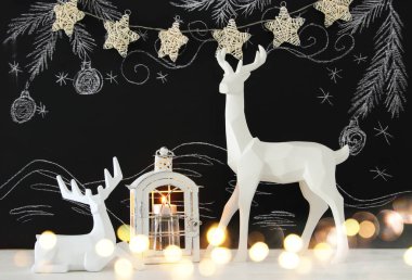 Kara tahta arka plan whith el üzerinde ahşap masa üzerinde beyaz Ren geyiği tebeşir illüstrasyonlar çizilmiş