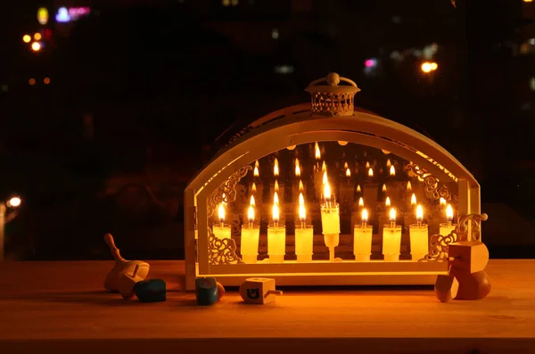 Image of jewish holiday Hanukkah background with menorah (traditional candelabra) and burning candles in front of the window. — Stock Photo, Image