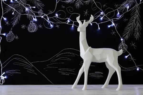 Kara tahta arka plan whith el üzerinde ahşap masa üzerinde beyaz Ren geyiği tebeşir illüstrasyonlar çizilmiş.