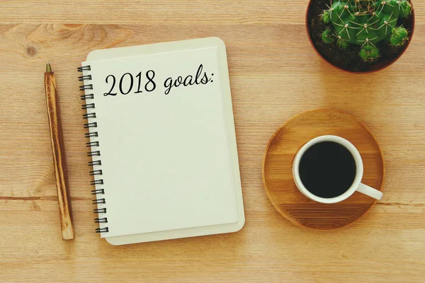 Top view 2018 goals list with notebook, cup of coffee on wooden desk. — Stock Photo, Image