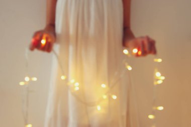 Garland Noel ışıkları tutan genç kadın soyut ve bokeh görüntüsünü.