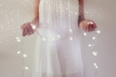 Garland Noel ışıkları tutan genç kadın soyut ve bokeh görüntüsünü.