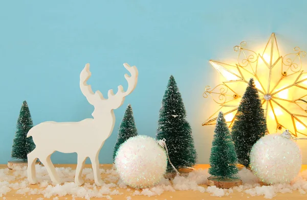 Görüntü Noel ağaçları ve karlı ahşap masa üzerinde Ren geyiği — Stok fotoğraf