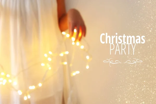 Immagine astratta e bokeh di una giovane donna che regge ghirlanda luci di Natale e tipografia: PARTY NATALE. Concetto invito vacanza . — Foto Stock