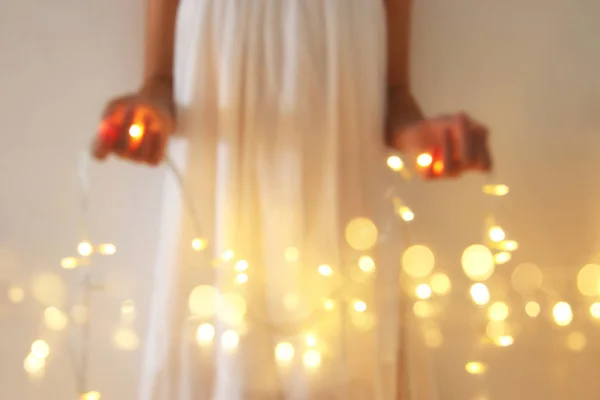 Abstract and bokeh image of young woman holding garland christmas lights. — Stock Photo, Image